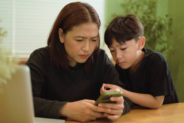 istock ​Boy is looking at a mobile phone with his mother. 2202031504
