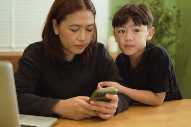 istock ​Boy is looking at a mobile phone with his mother. 2202031505