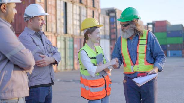 istock Logistics business partners handshake greeting before working together to make a business investment agreement or discussion about shipping plan, control loading of cargo and container truck according to the transport plan in loading yard. 2202032216