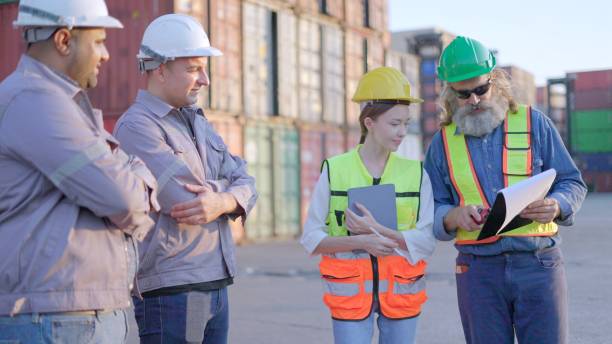 istock Team engineer industrial and dock workers checking shipping cargo freights in front of cargo at shipping container yard, talk about the transportation system and maintenance of containers in preparation for loading goods onto shipping ships. 2202032219
