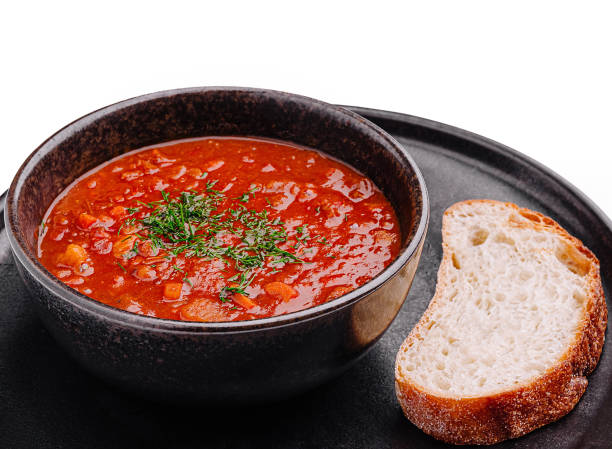 Delicious tomato soup served with fresh bread on a dark plate