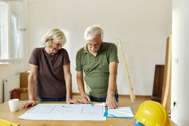 istock Senior couple examining blueprints during home renovation process. 2202034369