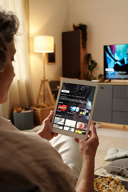istock Elderly Person Watching TV and Using Tablet for Entertainment 2202036600