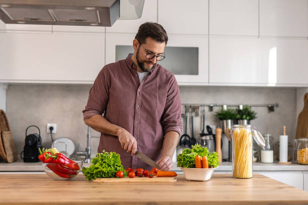 istock Handsome young man man stand at modern kitchen chop vegetables prepare fresh vegetable salad for dinner or lunch, young male cooking at home make breakfast follow healthy diet, vegetarian concept 2202036806