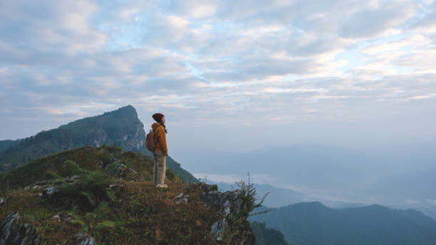 istock A woman standing on mountain peak on cloudy morning 2202037419