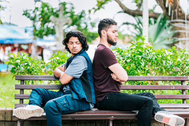 istock Two angry friends sitting on a park bench. Two friends arguing on a park bench 2202037728