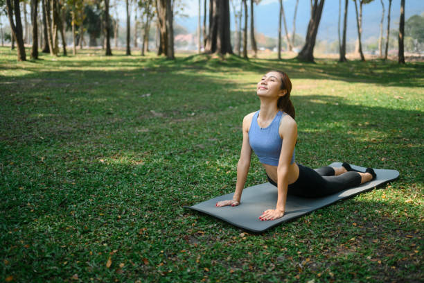 istock Young woman practicing yoga in cobra pose on mat at a peaceful park 2202038016