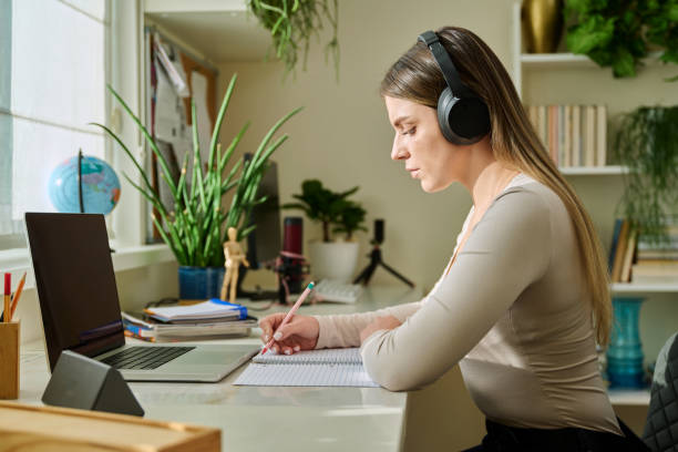istock Young woman student studying writing in notebook using laptop, at home 2202038333