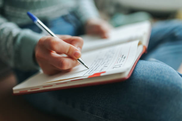 istock Student taking notes in a journal while seated comfortably at home 2202039424
