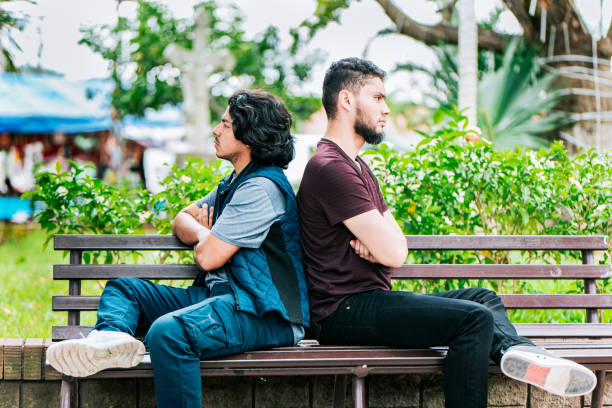 istock Two friends arguing on a park bench. Two angry friends sitting on a park bench 2202040568