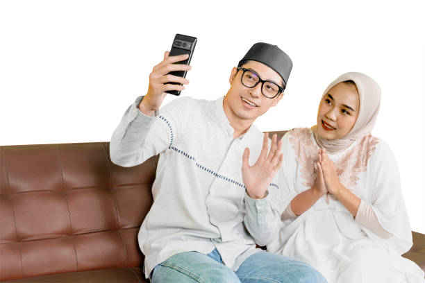 istock Happy Muslim Couple Taking a Selfie While Sitting on a Sofa, Celebrating a Special Occasion 2202040949