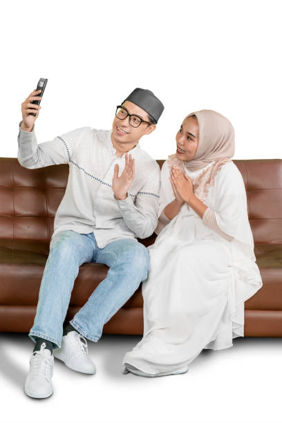 istock Cheerful Muslim Couple Taking a Selfie While Sitting on a Sofa, Celebrating Together 2202040951