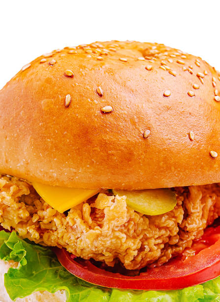 istock Crispy fried chicken sandwich with lettuce, tomato, and cheese on a sesame seed bun served on a white background 2202041438