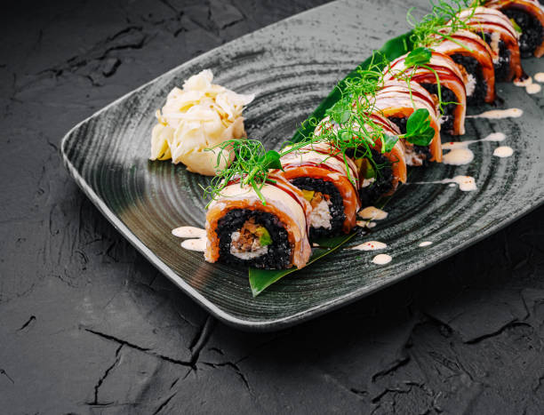 istock Exquisite sushi rolls beautifully arranged on a modern black plate with garnishes 2202041491