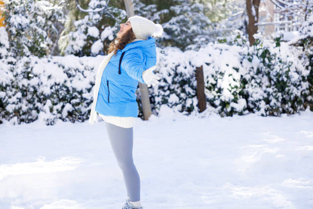 Young smiling woman enjoying a winter snowy day in the city