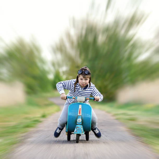 istock young boy is riding his scooter in spring season 2202042124