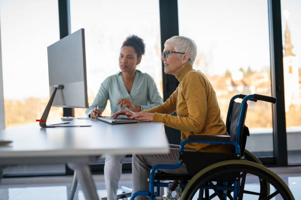 istock Disabled woman in wheelchair looking at computer, discussing startup project with interracial team 2202043878