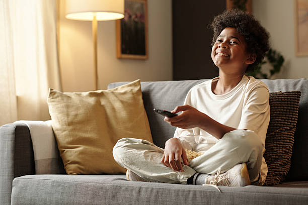 istock Smiling Child Watching Television on Comfortable Sofa 2202044787
