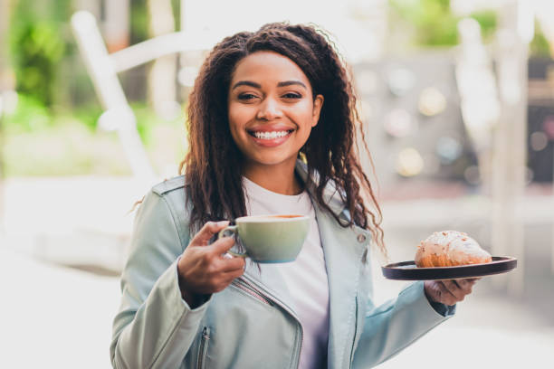 istock Charming young woman enjoying coffee and pastry outdoors on a sunny day 2202045045