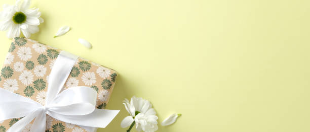 istock Happy Mothers Day banner design with gift box with floral pattern print, decorated white ribbon bow, daisy flowers on green background 2202046022