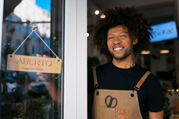 istock Smiling shopkeeper turning open sign on door 2202049535