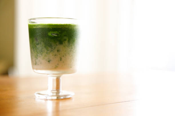 Iced matcha latte made from green tea powder and milk on wooden table. Selective focus. Popular matcha latte beverage in a glass.