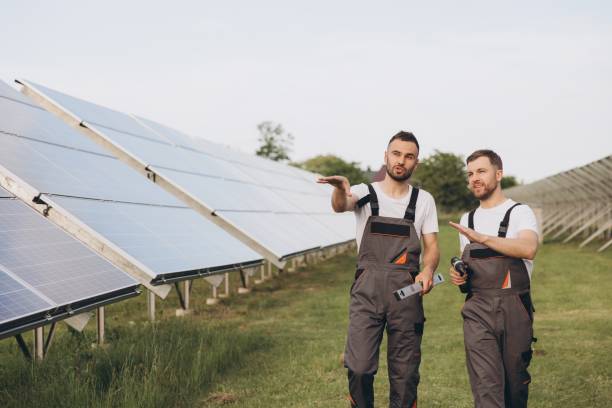 istock Two happy bearded workers in uniform discussing with each other and walking along solar panel farm 2202057036
