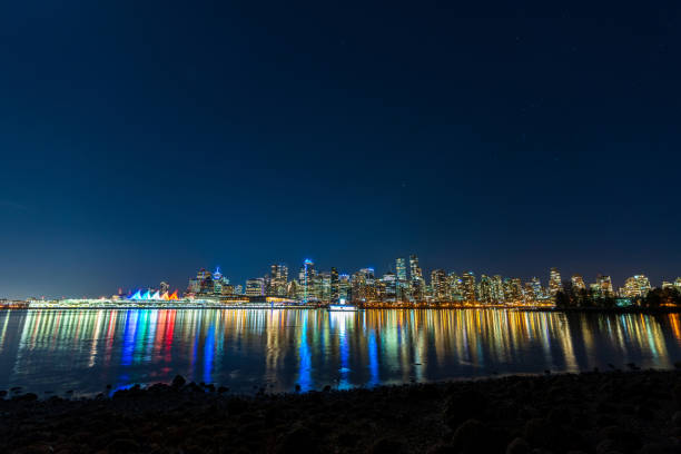 Vancouver downtown skyline night panorama. Colorful buildings lights reflections on waterfront harbor water surface. British Columbia, Canada.