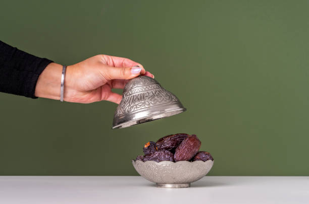Ramadan iftar table. Dates, green and black olives on the plate. Hazelnuts and almonds. Close-up photos with teapot and floral decor. Islam, muslim, iftar time, worship, prayer. Fasting.