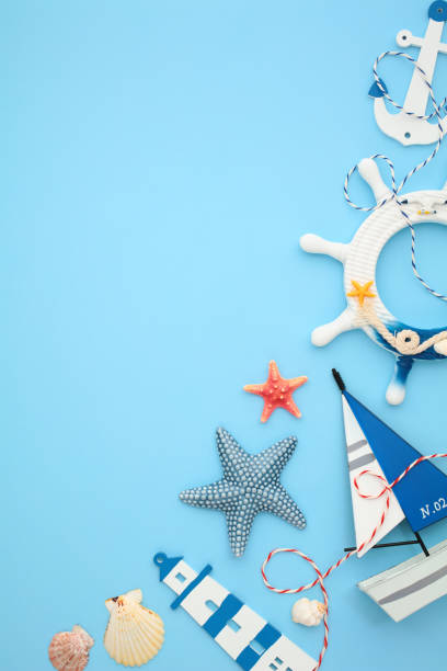 istock Nautical flat lay composition with lighthouse, anchor, starfishes, seashells and a sailboat on light blue background. 2202060117