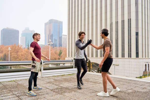 Three male athletes celebrating their workout with high fives, enjoying an active day together in the vibrant cityscape