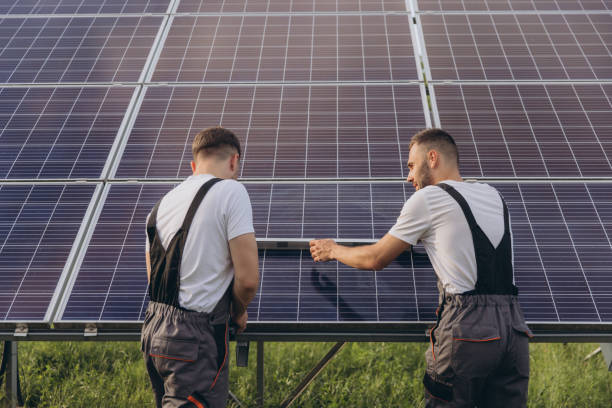 istock Two skilled workers or craftsmen wearing working gray uniforms, technicians are installing solar panels on a solar farm for clean energy and electricity supply 2202063460