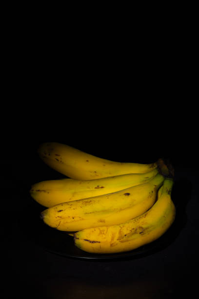 istock Vertical image of a bunch of bananas on a dark background 2202063606