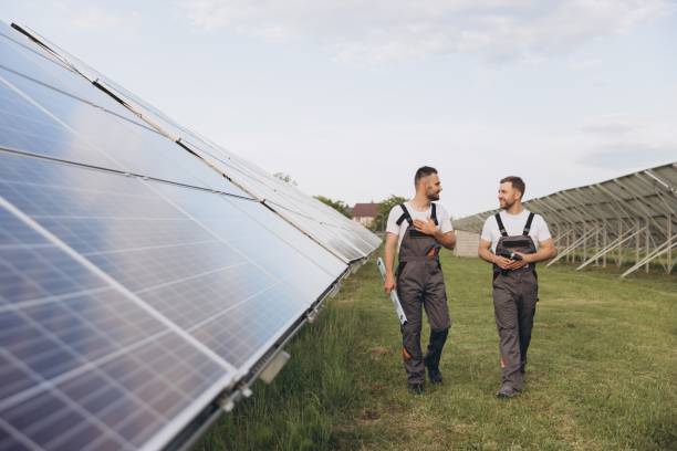 istock Two happy bearded workers in uniform discussing with each other and walking along solar panel farm 2202063701