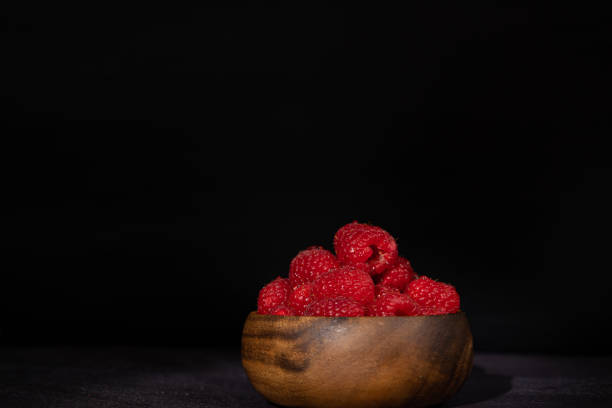 A wooden plate holding bunches of fresh red grapes resting on a light-colored striped tablecloth