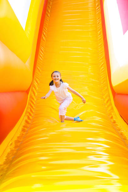 Happy Little Girl Having Lots of Fun on a Jumping Castle While Sliding