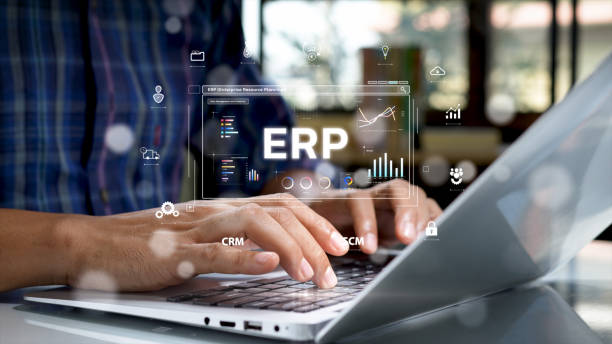 istock Close-up of hands typing on a laptop keyboard with a futuristic digital interface displaying ERP (Enterprise Resource Planning) system, analytics, and business management icons. 2202067348