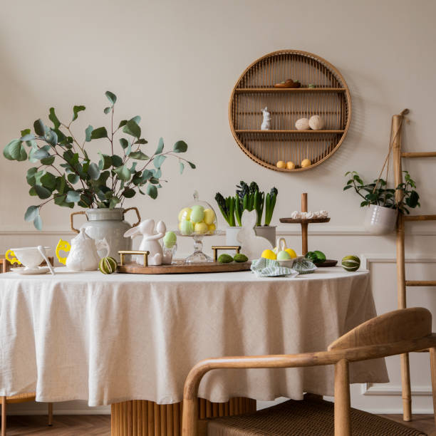 istock Warm and spring dining room interior with easter accessories, round table, vase with green leaves, cake, colorful eggs, rabbit sculpture 2202068940