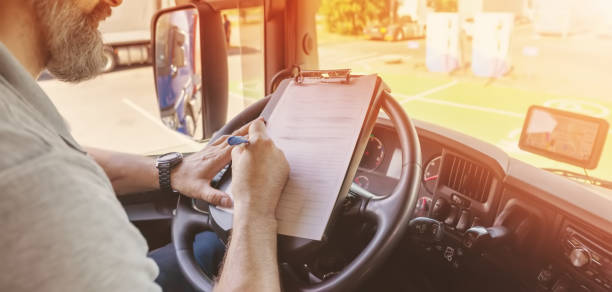 istock Truck driver sitting in the car and writing documents. 2202068974