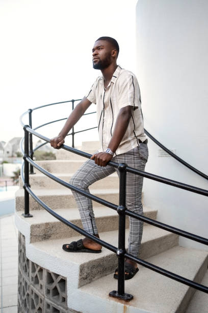 istock African man standing on spiral steps leaning on railing outdoors 2202070193