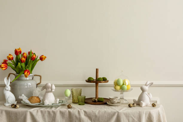 istock Creative composition of easter living room interior with copy space, vase with spring tulips, easter bunny sculpture, elegant cup, colorful easter eggs and personal accessories. Home decor. Template. 2202072729