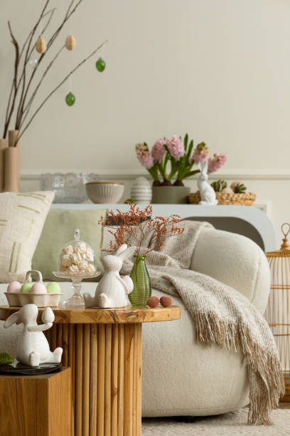 istock Warm and cozy composition of easter living room interior with coffee table, white sofa, colorful easter eggs, easter bunny, hyacinth, vase with branch and personal accessories. Home decor. Template. 2202074489