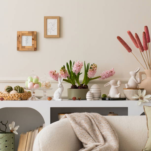 istock Interior design of easter living room interior with mock up poster frame, stylish white sideboard, hyacinth, easter bunny, vase with dried flowers and personal accessories. Home decor. Template. 2202074661