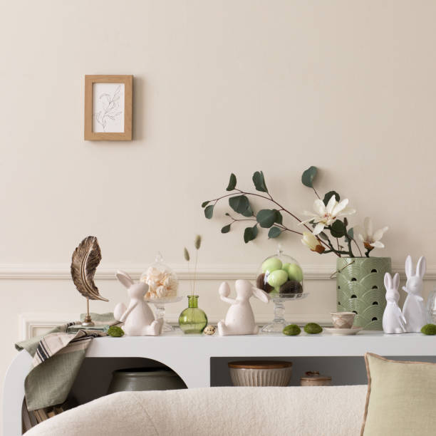 istock Interior design of easter living room interior with mock up poster frame, stylish sideboard, colorful easter eggs, easter bunny sculpture, vase with leaves and personal accessories Home decor Template 2202074678