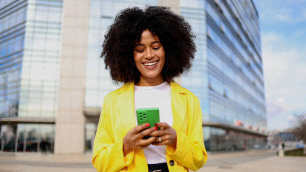 istock Joyful Afro woman strolling through the city while browsing her phone 2202074909