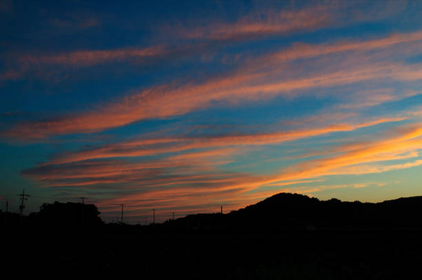 istock Clouds colored red in the sunset and a countryside field in darkness. 2202081064