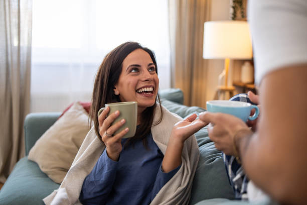 istock Couple wearing pajamas relaxing on sofa drinking coffee and talking 2202087998