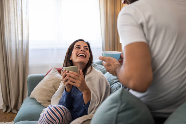 istock Couple wearing pajamas relaxing on sofa drinking coffee and talking 2202088018