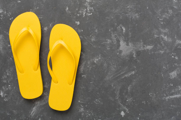 istock Bright yellow flip-flops on concrete background, top view. Summer concept 2202089049