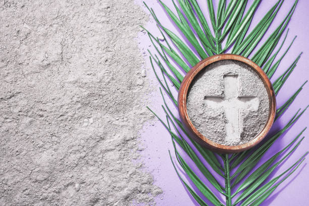 istock Bowl with ashes and cross print on purple background. Ash Wednesday 2202089585